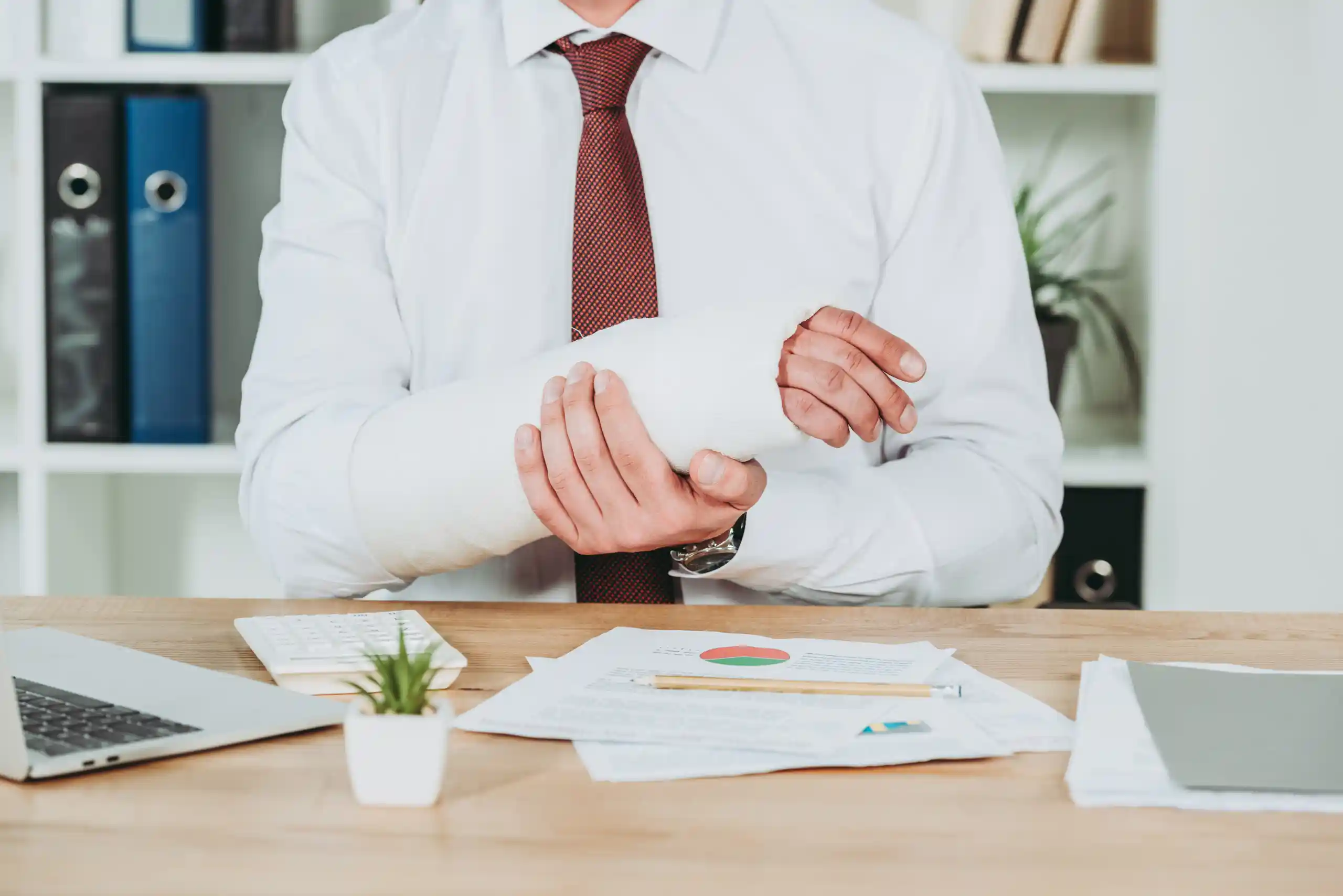 Worker holding injured hand while sitting at their desk